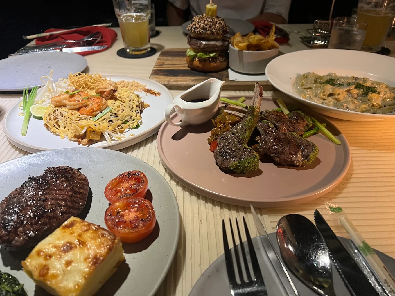 Group of diners sharing a variety of Thai dishes at a restaurant table.