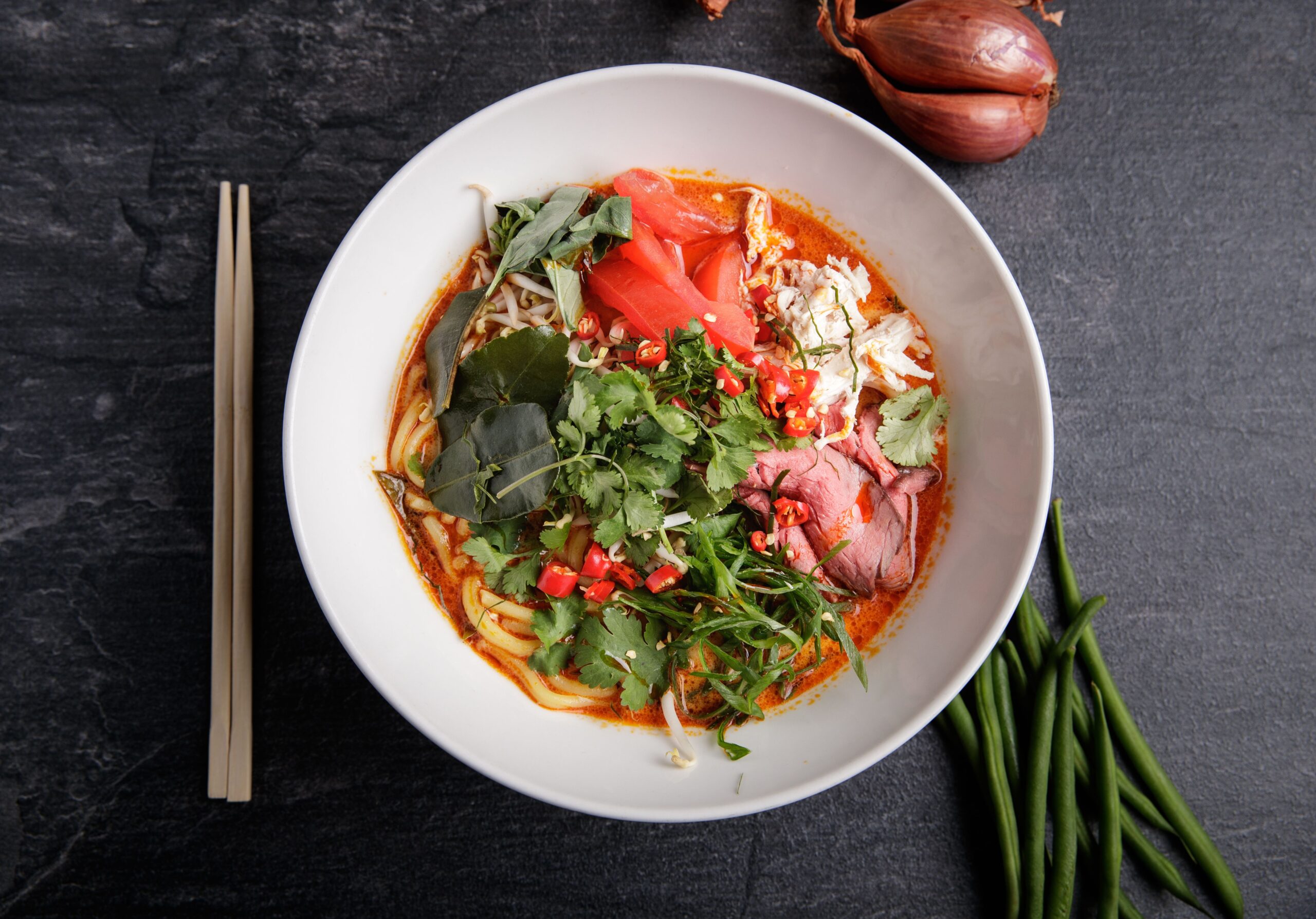 Thai noodle soup with noodles, herbs, vegetables, and flavorful broth.